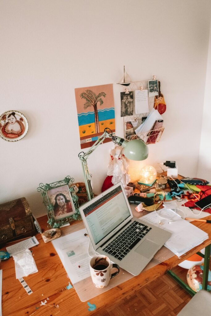 A well-used desk setup with a laptop, lamp, and personal touches, ideal for remote work inspiration.