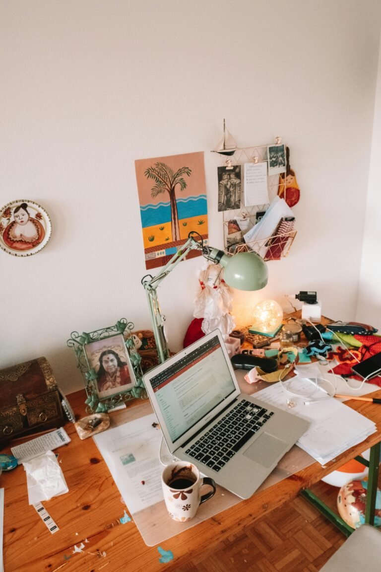 A well-used desk setup with a laptop, lamp, and personal touches, ideal for remote work inspiration.